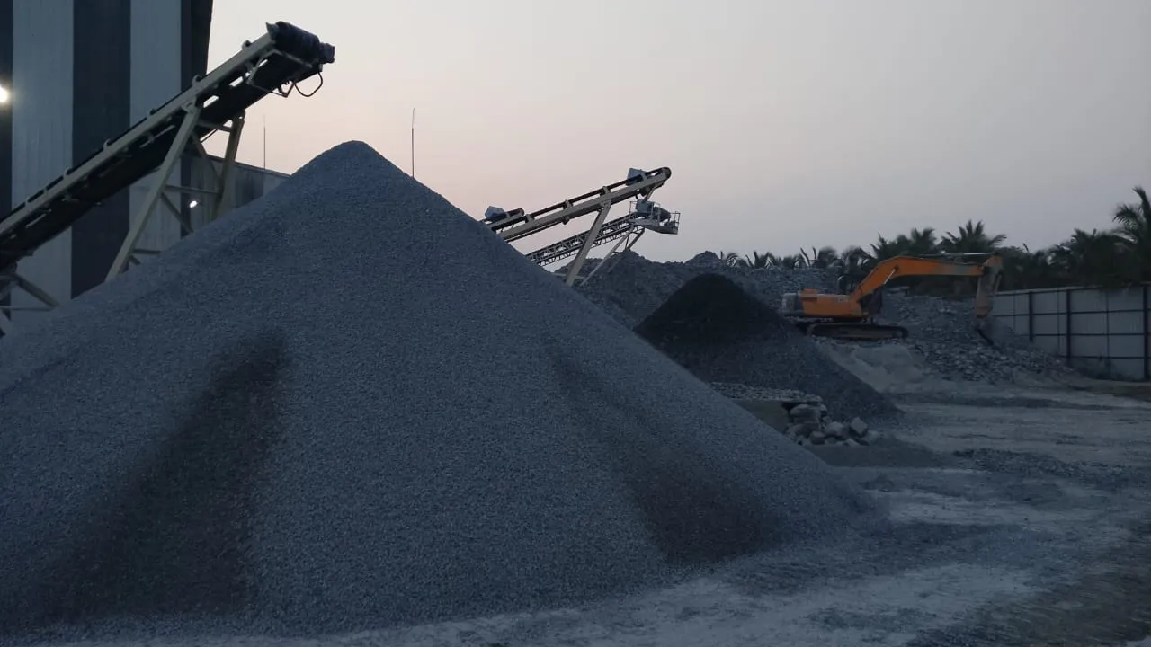 Excavator working on blue metals aggregate pile at dusk at Tirupati Balaji Blue Metals facility, Virudhunagar