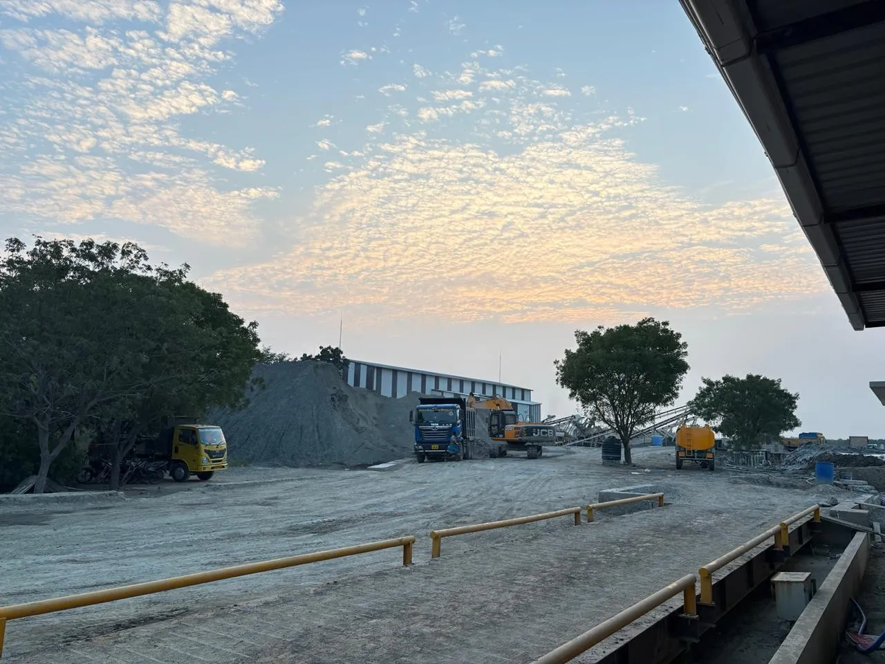 Weighbridge, tipper trucks, and excavator at Tirupati Balaji Blue Metals LLP plant yard in Virudhunagar, Tamil Nadu — showing the full scale of operations